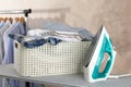 Basket with clean laundry and iron on ironing board Royalty Free Stock Photo
