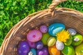 A basket with colorful Easter eggs decorations and flowers on grass with clovers