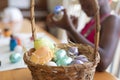 Basket of colourful eggs with african american girl painting in the background