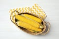 Basket of corn cobs on white wooden table, flat lay Royalty Free Stock Photo