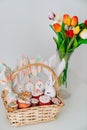 basket with decorated eggs and Easter cakes on table with bouquet of tulips Royalty Free Stock Photo