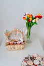 basket with decorated eggs and Easter cakes on table with bouquet of tulips Royalty Free Stock Photo