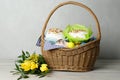 Basket with delicious Easter cakes, dyed eggs and flowers on light wooden table Royalty Free Stock Photo