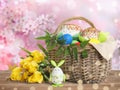Basket with delicious Easter cakes, dyed eggs and flowers on wooden table outdoors Royalty Free Stock Photo