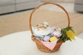 Basket with delicious Easter cakes, dyed eggs and flowers on white table indoors. Space for text Royalty Free Stock Photo