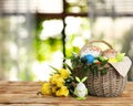 Basket with delicious Easter cakes, dyed eggs and flowers on wooden table indoors. Space for text Royalty Free Stock Photo