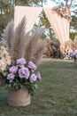 A basket with dried pampas leaves and pastel pink roses. Decor for an aisle of a rustic garden wedding ceremony Royalty Free Stock Photo