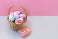 Basket with Easter eggs on a delicate pink background, next to a pink box with a gift. Royalty Free Stock Photo