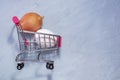 Shopping toy trolley with egg and onions on gray background, with copy space. The concept of healthy eating
