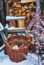 Basket with fire wood near wooden shed in winter