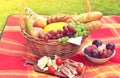 Basket with Food Fruit Bakery Cheese Ham Tomato Picnic Green Grass Toned Photo Royalty Free Stock Photo