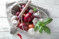 Basket with fresh garlic, basil leaves and onion on white wooden background Royalty Free Stock Photo