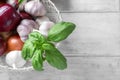Basket with fresh garlic, basil leaves and onion on white wooden background Royalty Free Stock Photo