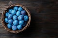 Basket of fresh, ripe blue plums on wooden background Royalty Free Stock Photo