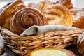 Basket of freshly baked dinner rolls with tableware in wooden background. Macro with shallow dof Royalty Free Stock Photo