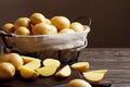 Basket full of fresh, young potatoes board, towel and knife on wooden background Royalty Free Stock Photo