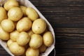 Basket full of fresh, young potatoes board, towel and knife on wooden background Royalty Free Stock Photo