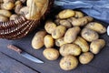 Basket full of fresh, young potatoes , towel and knife on wooden background, top view Royalty Free Stock Photo