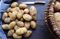 Basket full of fresh, young potatoes , towel and knife on wooden background, top view Royalty Free Stock Photo