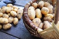 Basket full of fresh, young potatoes , towel and knife on wooden background, top view Royalty Free Stock Photo