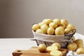 A basket full of fresh, young potatoes on a wooden table, a knife and a kitchen board Royalty Free Stock Photo