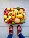 Basket full of fruit on the floor with person standing next to it Royalty Free Stock Photo
