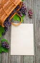 Basket with grapes on rustic wood with sheet of paper template in centre. Vertical wine making background