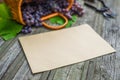 Basket with grapes beside secateurs on vintage rustic wooden table. Closeup Old paper template in centre wine making Royalty Free Stock Photo