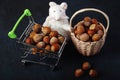 Basket Hazelnuts, white mouse toy on wooden backdrop. heap or stack of hazelnuts