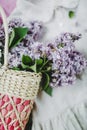 Basket of lilacs flowers, pastel pink and white summer dress. Women's stylish outfit. Flat lay, top view. Flowers