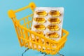 Basket loaded with vitamin D or fish oil capsules in a plate on a blue background. The concept of medicine and sales