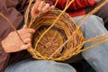 Basket maker weaves wood strands in circular basket.