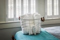 A basket of organized clean rolled white towels for guests sitting on a bed in a guest bedroom Royalty Free Stock Photo