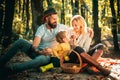 Basket with picnic meal and toys for the kid. Happy family of three lying in the grass in autumn. The concept of a happy Royalty Free Stock Photo