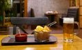 Basket of potato chips and dip with a glass of chilled draft beer on the wooden table