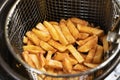 a basket of potatoes is taken out of the deep fryer. cooking french fries Royalty Free Stock Photo