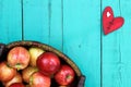 Basket of red apples on wood table with red heart