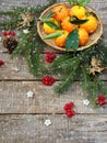 Basket of ripe mandarins, spruce branches and christmas toy on a wooden background. selective focus. copy space Royalty Free Stock Photo