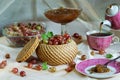 Basket of ripe red gooseberry and jam on a laid table during tea time