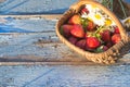 Basket with ripe strawberries and white camomiles on old blue paint wooden background. Royalty Free Stock Photo