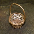 Basket round with a handle made of yellow vines on a background of brown parquet. Folk craft, design, structure