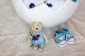 Basket shell of Easter eggs, flat shoes baby boy and a teddy bear with a heart close-up, requisites for a photo session of a newbo Royalty Free Stock Photo