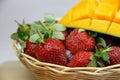 a basket of strawberries and mangoes on the cutting board on white background Royalty Free Stock Photo