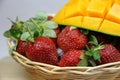 a basket of strawberries and mangoes on the cutting board on white background Royalty Free Stock Photo