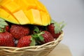 a basket of strawberries and mangoes on the cutting board on white background Royalty Free Stock Photo