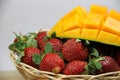 a basket of strawberries and mangoes on the cutting board on white background Royalty Free Stock Photo