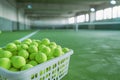 Basket of tennis balls on green synthetic grass indoor tennis court Royalty Free Stock Photo