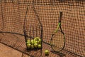 Basket tennis balls and racket against net on clay court Royalty Free Stock Photo