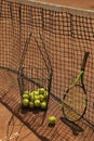 Basket with tennis balls and racket against net clay court Royalty Free Stock Photo