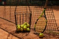 Basket with tennis balls and racket against net on clay court Royalty Free Stock Photo